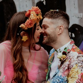 Bride in pink kissing groom in floral suit