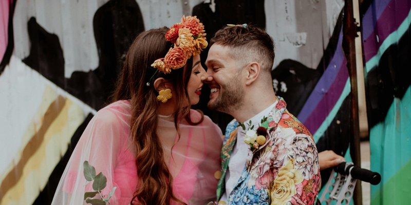 Bride in pink kissing groom in floral suit