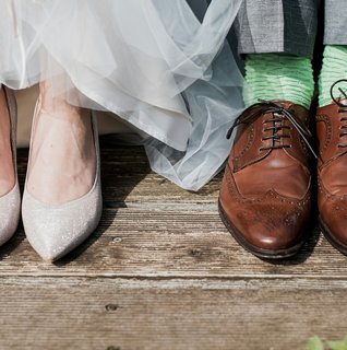 Bride and groom wedding shoes detail shot with bride heels and groom brown dress shoes with green socks