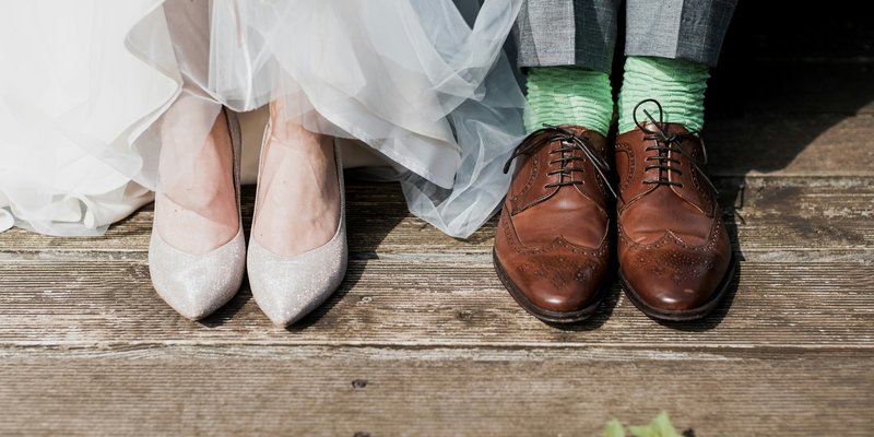 Bride and groom wedding shoes detail shot with bride heels and groom brown dress shoes with green socks