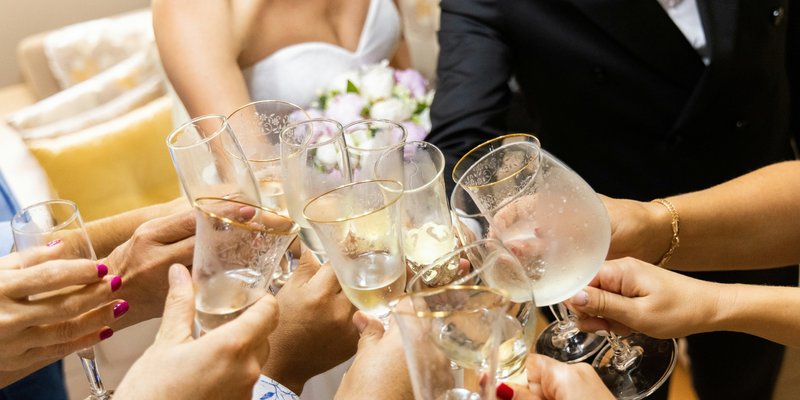 **Alt Text:** Close-up of wedding guests raising champagne glasses for a celebratory toast, capturing the joyful moment of a Central PA wedding reception.