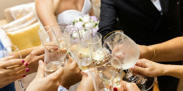 **Alt Text:** Close-up of wedding guests raising champagne glasses for a celebratory toast, capturing the joyful moment of a Central PA wedding reception.