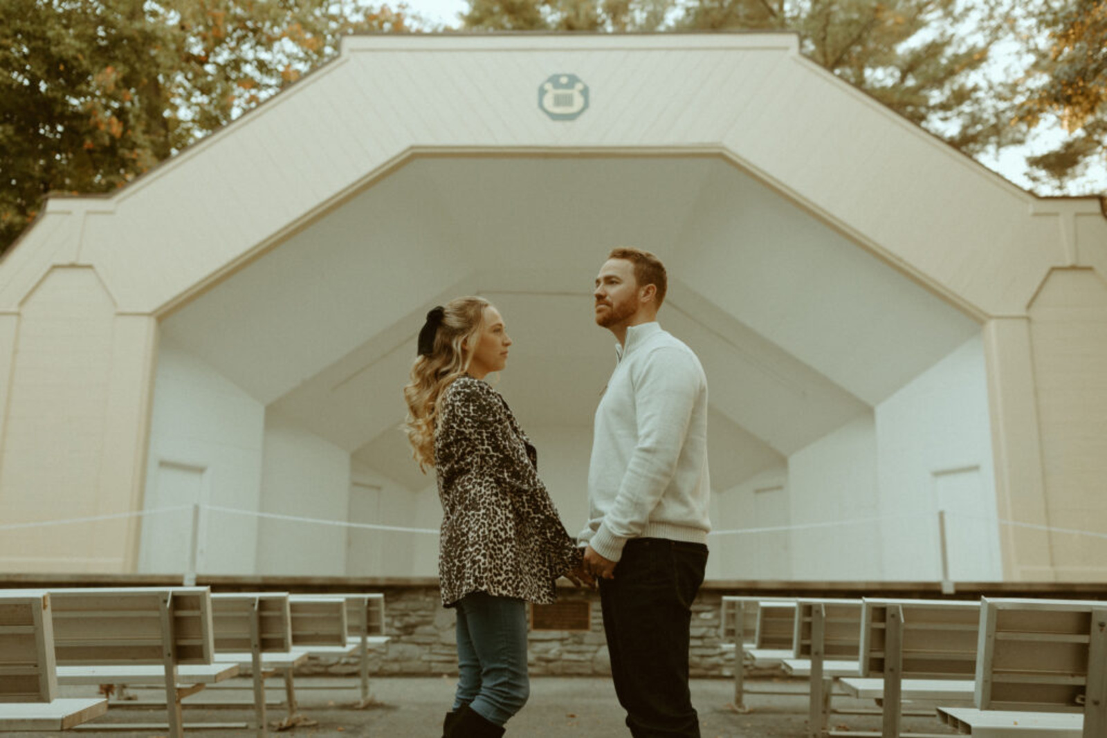 Couple standing hand-in-hand in front of the white bandstand at Lititz Springs Park during their fall engagement session in Lititz, Pennsylvania.