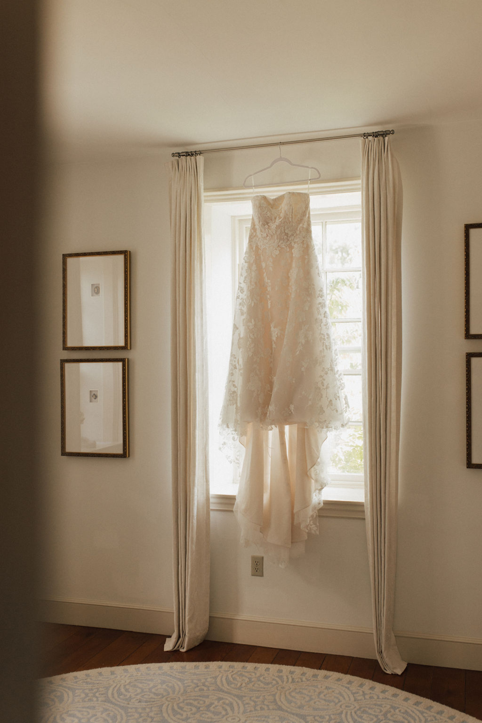 Lace strapless wedding dress with long train hangs in the window