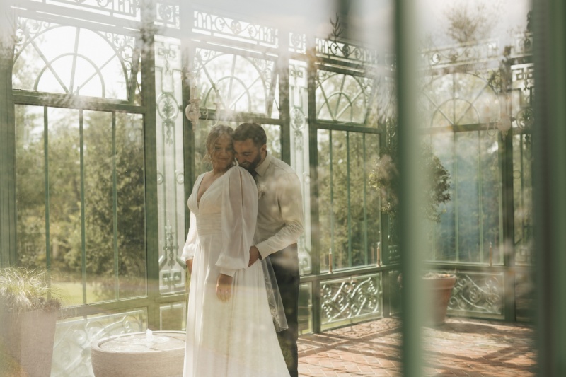 Bride and groom sharing a quiet moment inside a glass greenhouse during their fall wedding at St. Michael’s Vineyard.