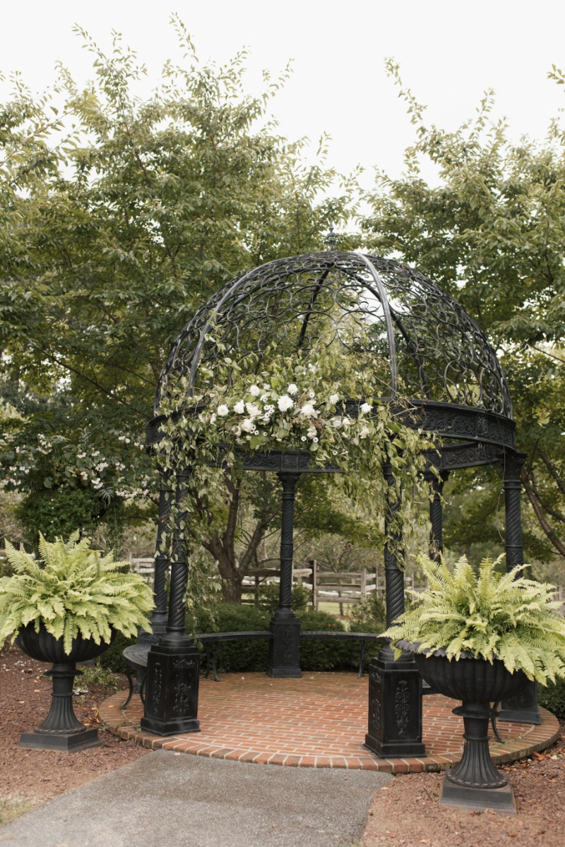 Black wrought-iron garden gazebo decorated with white flowers and greenery at St. Michael’s Vineyard.