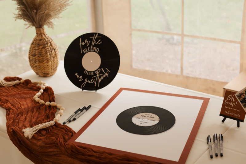 Music-themed wedding guest book featuring a vinyl record design, rust-colored fabric, and handwritten guest messages.
