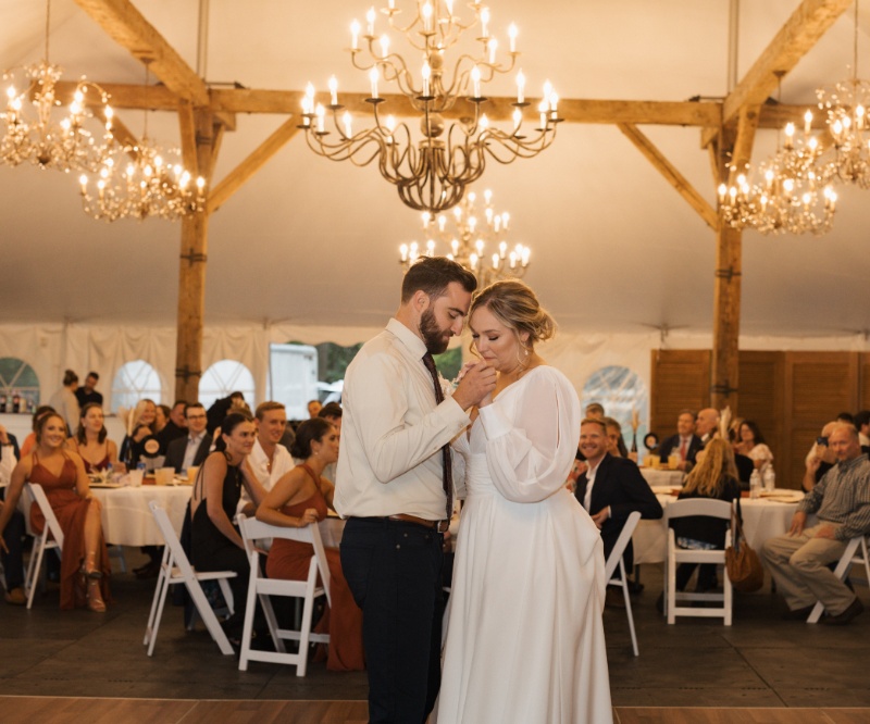 Bride and groom sharing their first dance beneath glowing chandeliers during their fall wedding reception at St. Michael’s Vineyard.