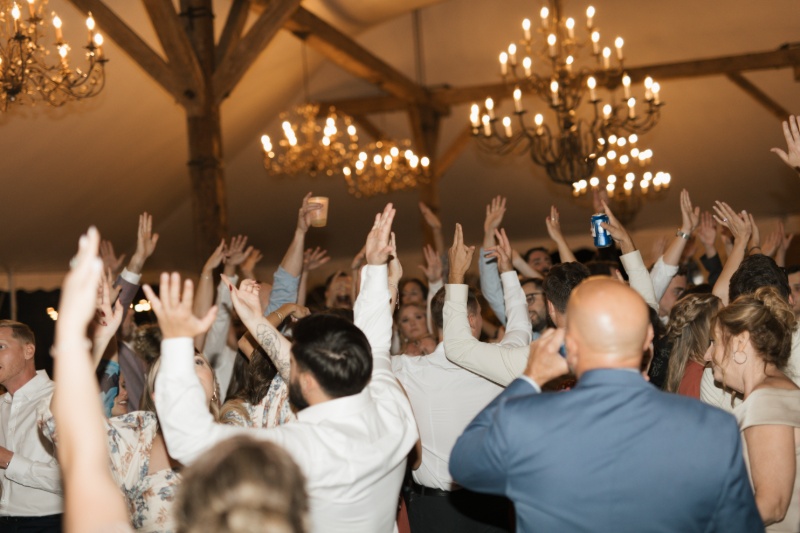 Wedding guests dancing beneath glowing chandeliers during a lively reception at St. Michael’s Vineyard.