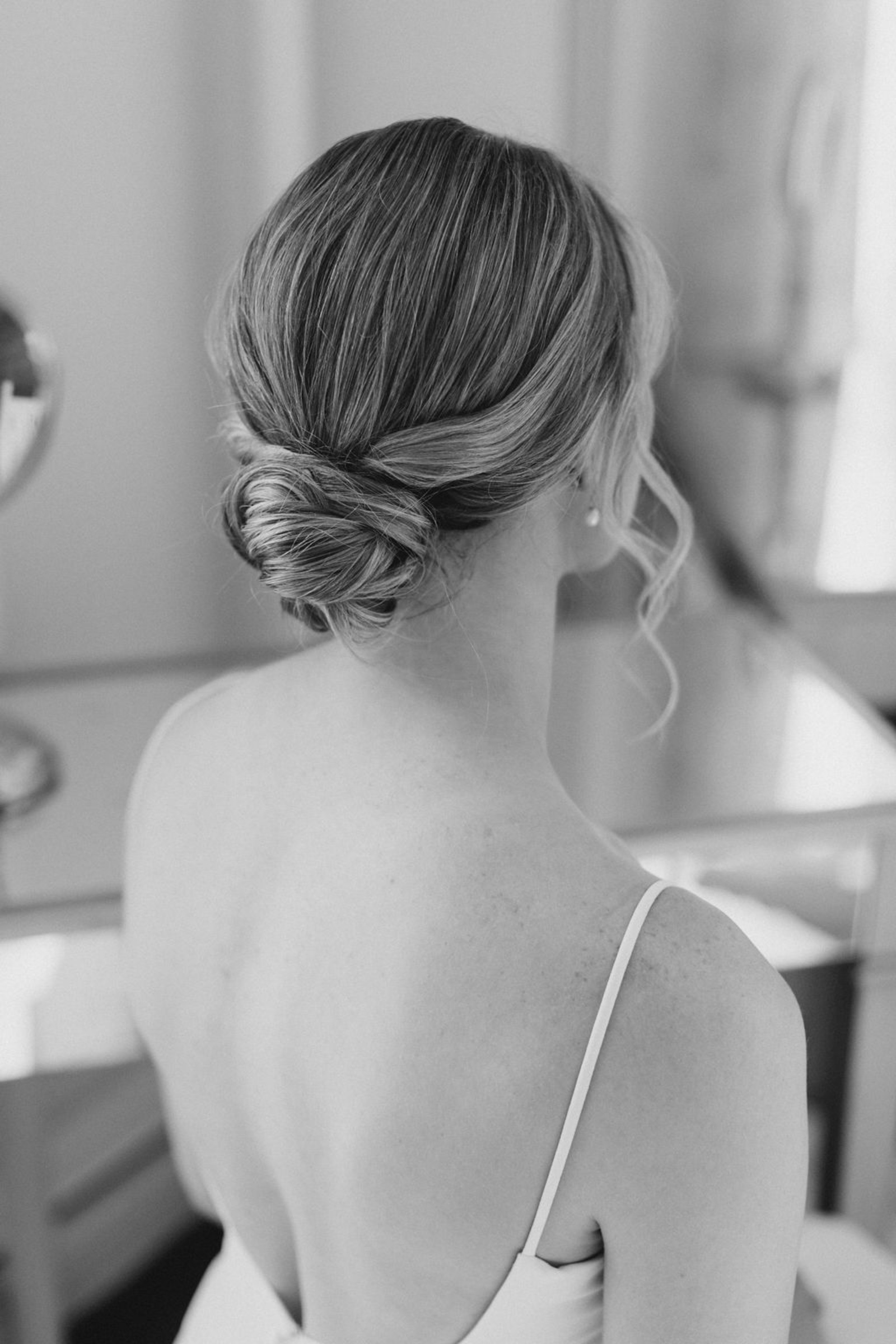 A black-and-white photo of the bride’s timeless twisted low bun hairstyle, captured as she gets ready inside Historic Ashland’s bridal suite.