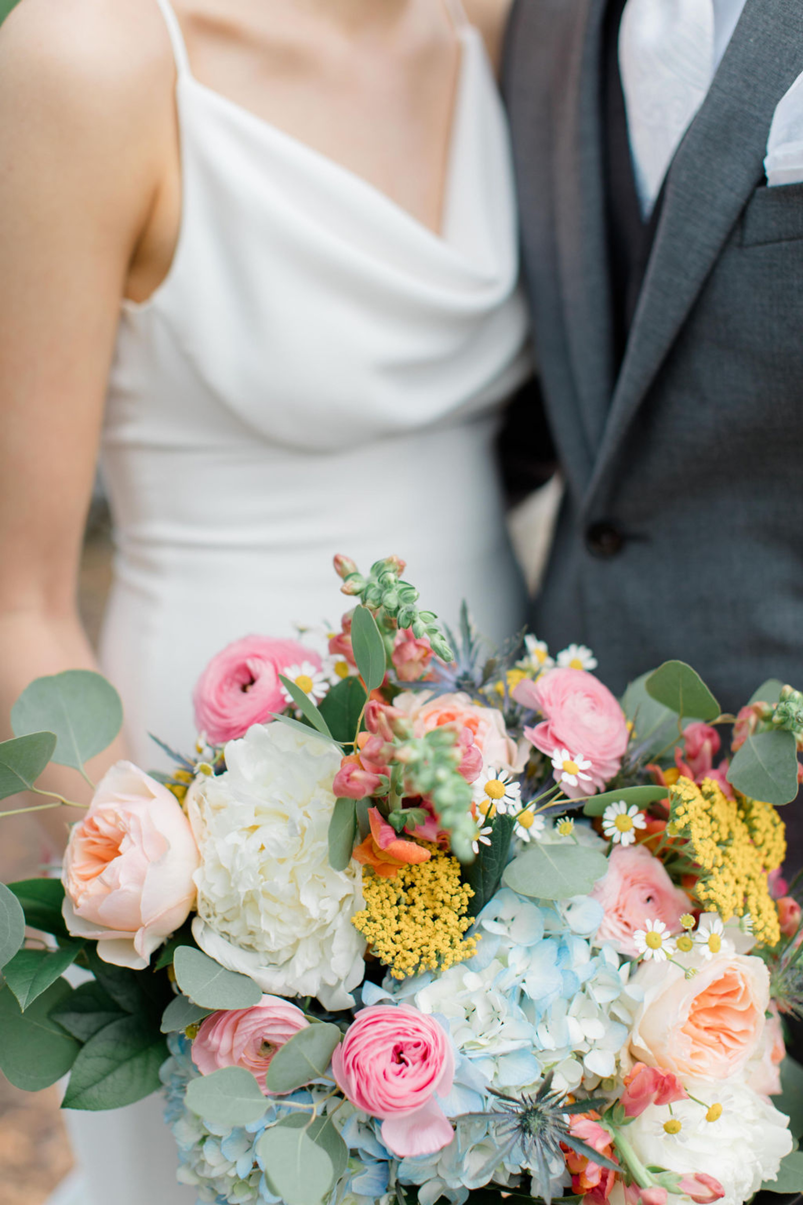 A close-up of the bride’s bouquet featuring peonies, ranunculus, hydrangeas, and wildflowers in shades of pink, peach, and yellow — designed for a spring wedding at Historic Ashland.