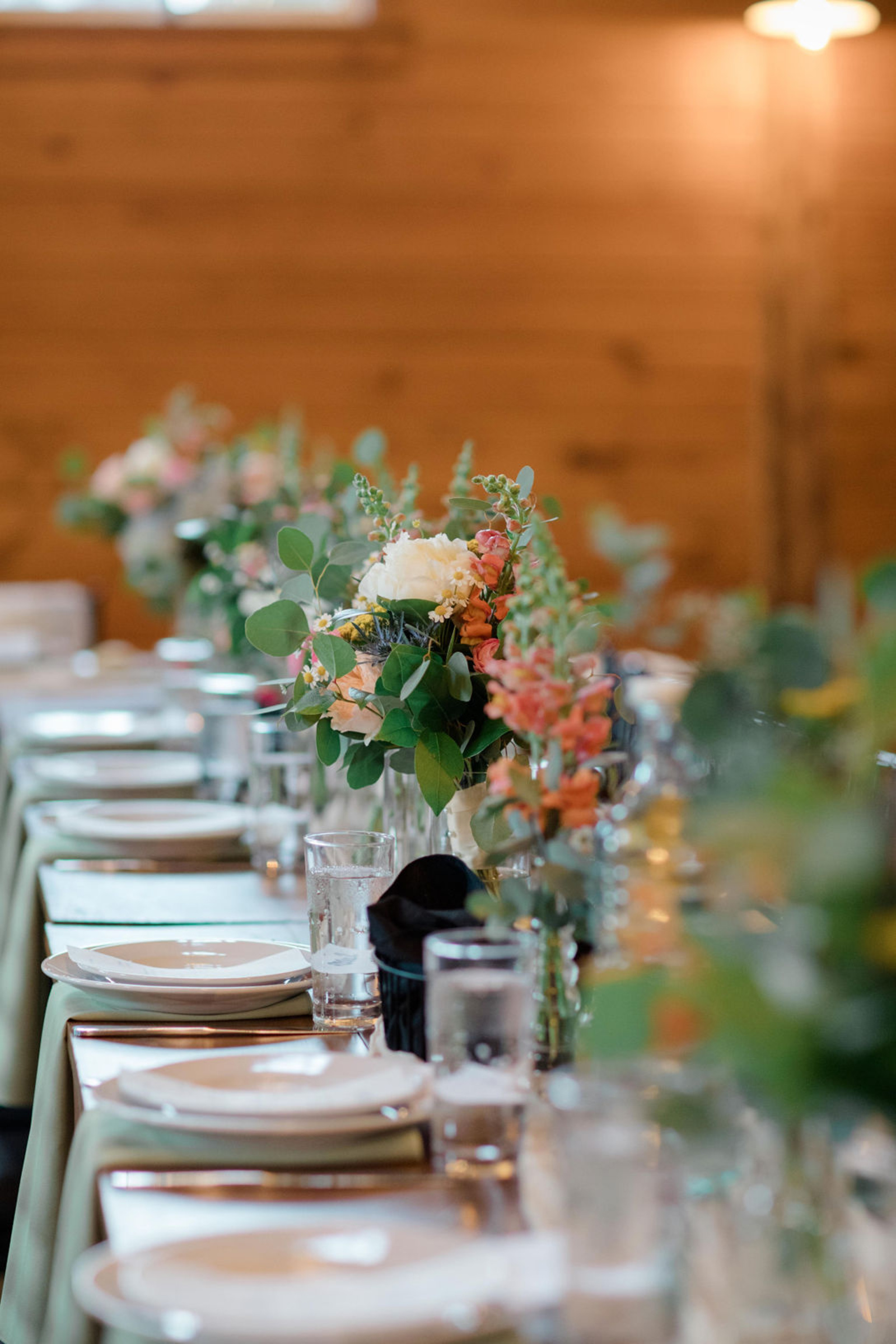Close-up of floral arrangements featuring peonies, snapdragons, and eucalyptus greenery adorning the reception tables at Historic Ashland.