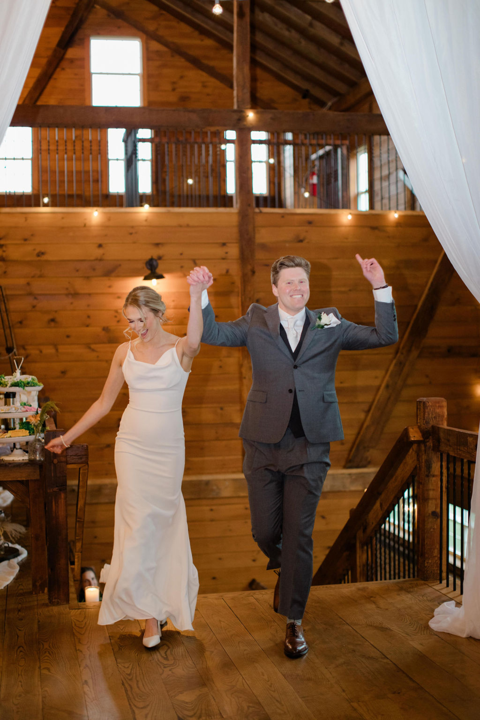 Bride and groom enter the rustic reception at Historic Ashland hand-in-hand, celebrating as guests cheer.
