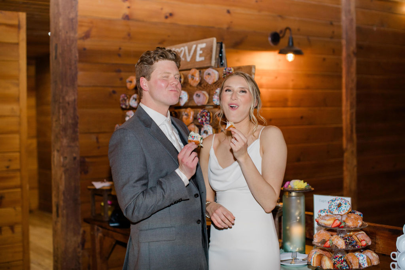 Bride and groom share a fun and playful moment enjoying donuts from their dessert display during their wedding reception at Historic Ashland in Central Pennsylvania.