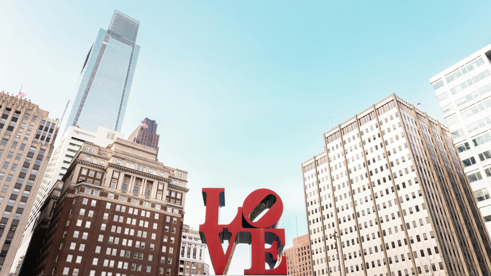Iconic red LOVE sculpture in Philadelphia’s LOVE Park surrounded by tall city buildings under a bright blue sky — a perfect backdrop for a Central PA bachelorette weekend getaway.