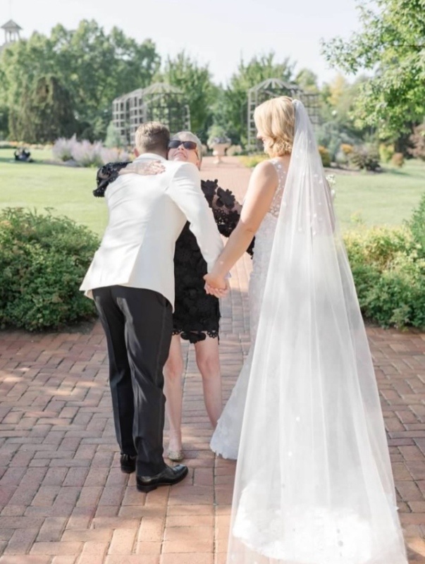 Groom and bride hugging wedding planner, Susan Moran.