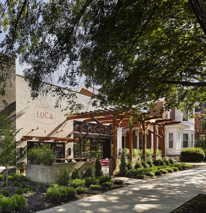 Exterior of LUCA restaurant in Lancaster, PA, with outdoor patio seating, wooden pergolas, and landscaped greenery.