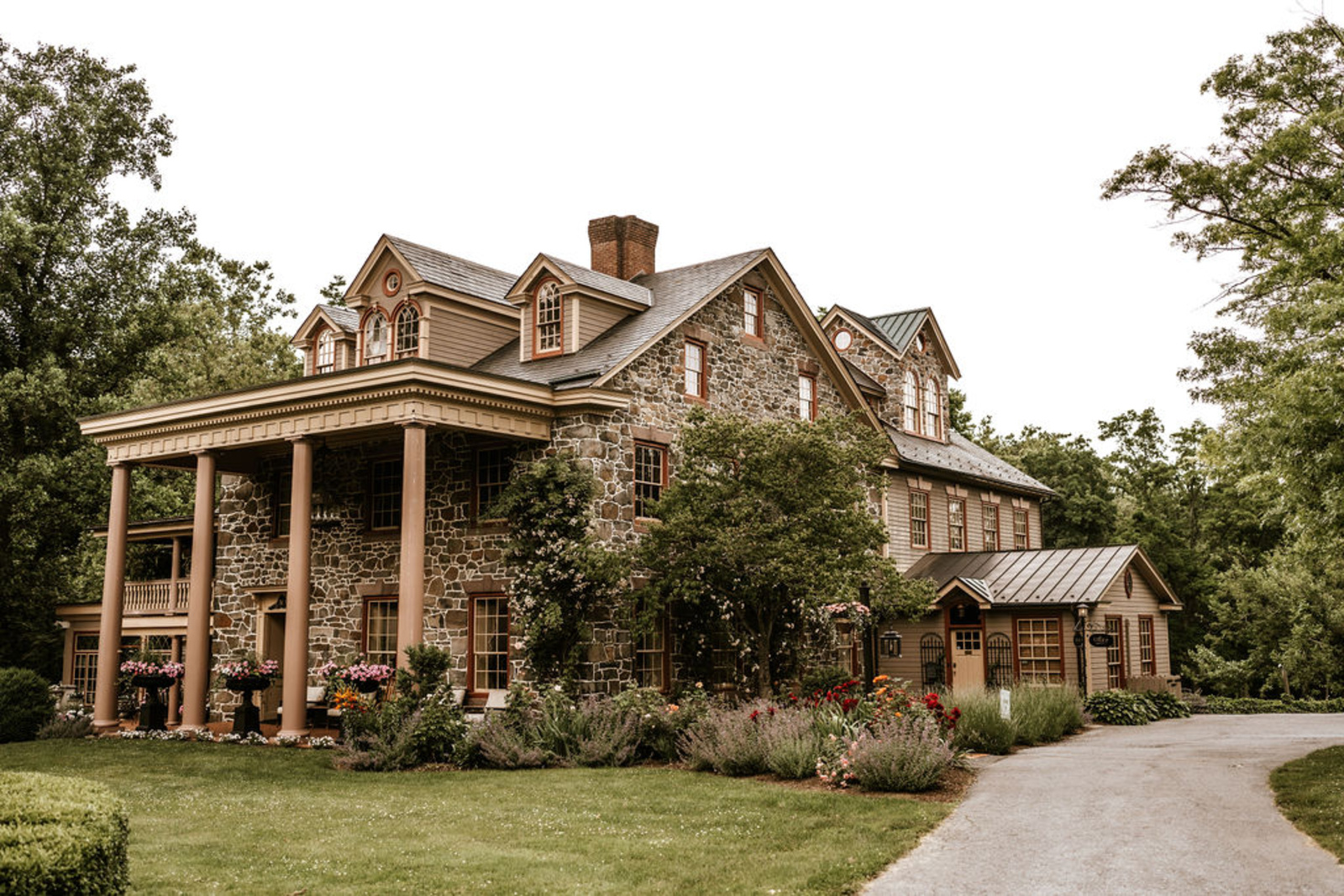The elegant 1742 stone mansion at Moonstone Manor surrounded by lush gardens and greenery, a popular Central Pennsylvania wedding venue.