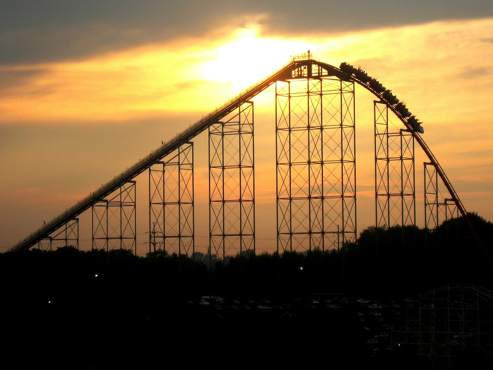 A roller coaster climbs toward the peak at sunset in Hersheypark, Pennsylvania, creating a dramatic silhouette against the glowing sky — perfect for thrill-seeking brides on a bachelorette getaway.