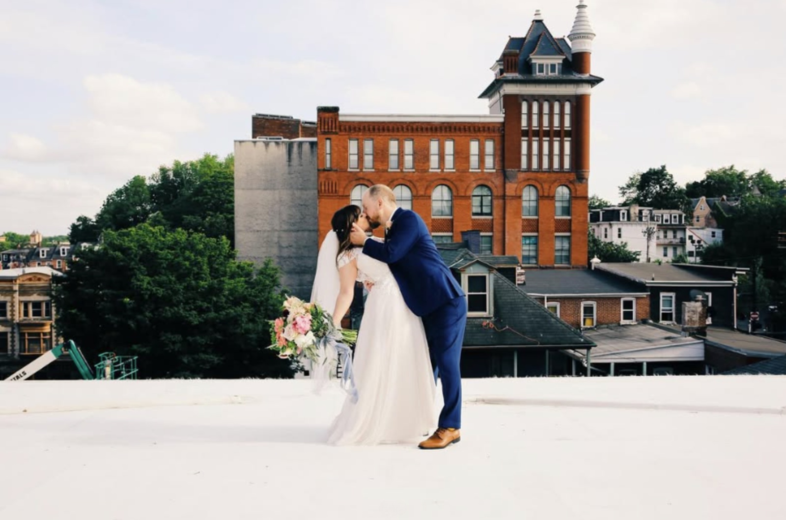 Rooftop Wedding Portrait at Mulberry Art Studios in Lancaster, PA Bride and groom kissing on a rooftop overlooking historic brick buildings in downtown Lancaster, PA.