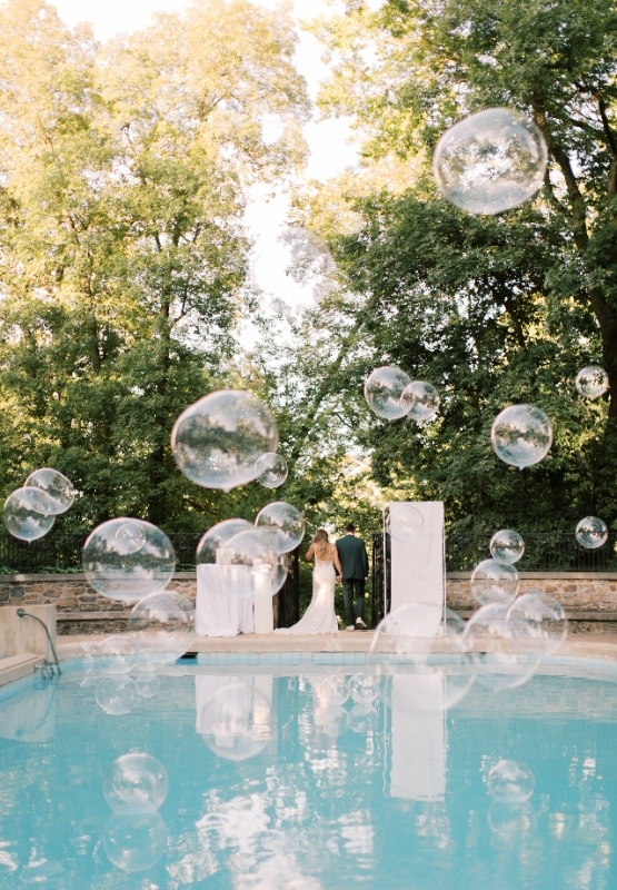 Outdoor wedding reception by a pool with oversized bubbles floating through the air, showcasing a fun and interactive guest experience at a Central PA wedding.