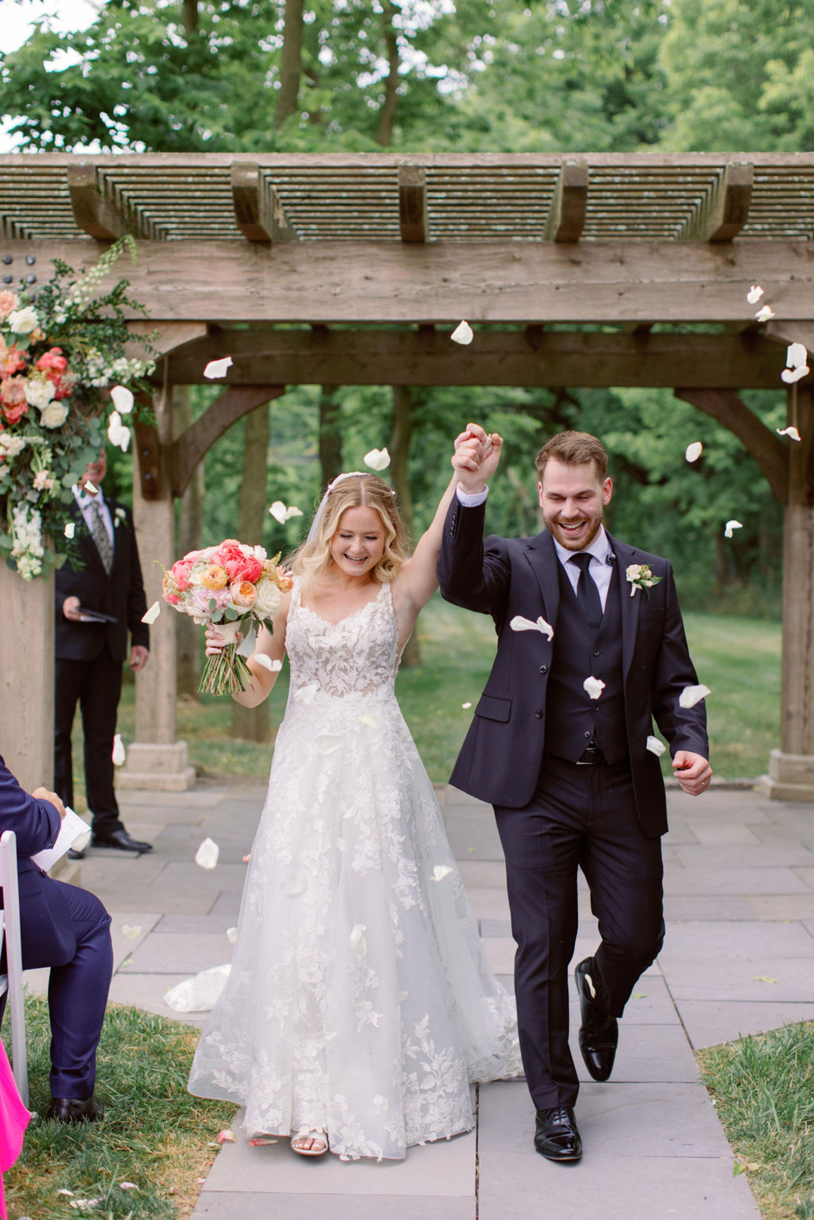 Bride and groom walking back down the aisle after their outdoor ceremony at Historic Ashland as guests toss flower petals around them.