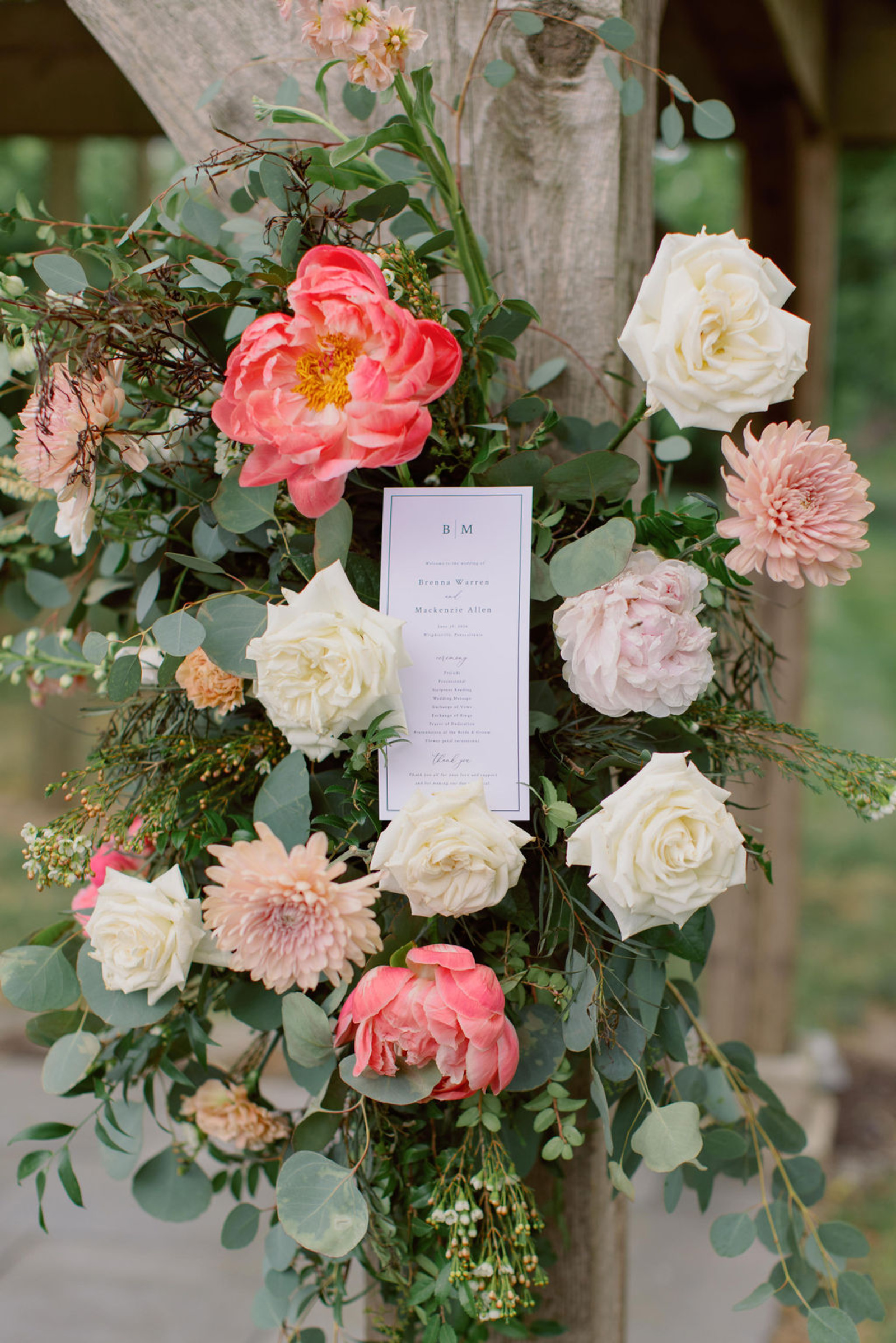 Coral, blush, peach, and white ceremony florals decorating the wooden pergola during an outdoor wedding ceremony at Historic Ashland.