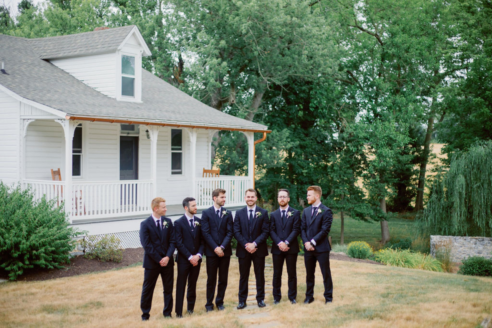 Groom and groomsmen in navy tuxes posing outside Historic Ashland before the wedding ceremony.