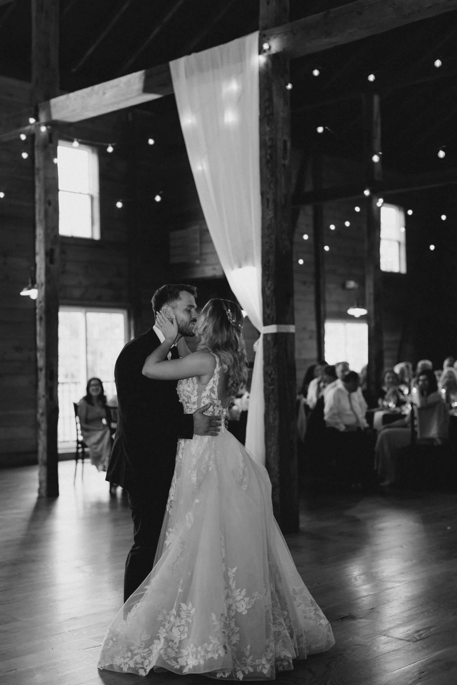 Bride and groom sharing a romantic first dance inside Historic Ashland’s warmly lit barn reception space.