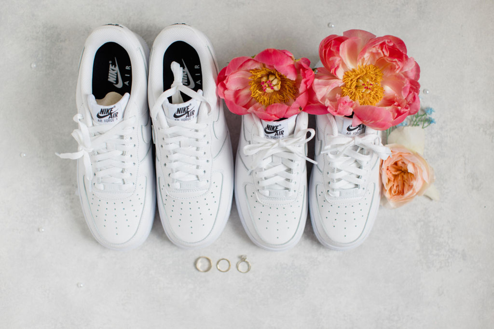White Nike Air Force 1 sneakers styled with coral and peach florals alongside wedding rings for a romantic early summer wedding at Historic Ashland.