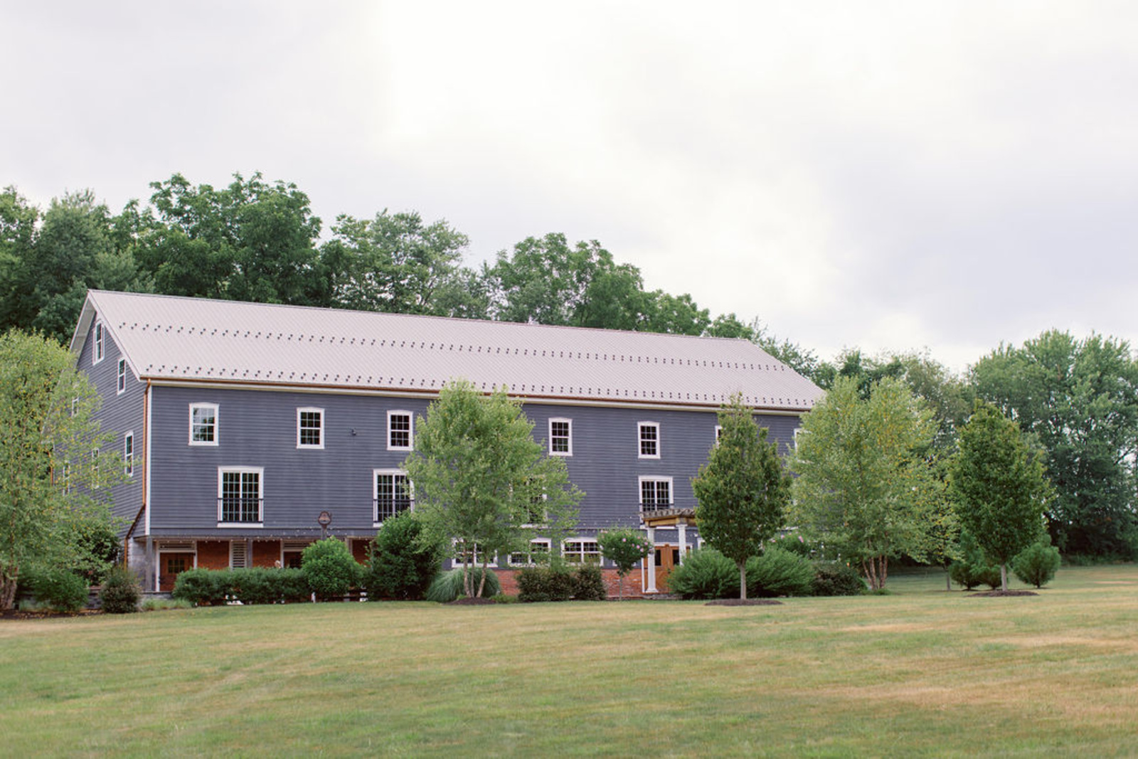 Exterior view of Historic Ashland’s reception barn surrounded by greenery during an early summer wedding in Central Pennsylvania.