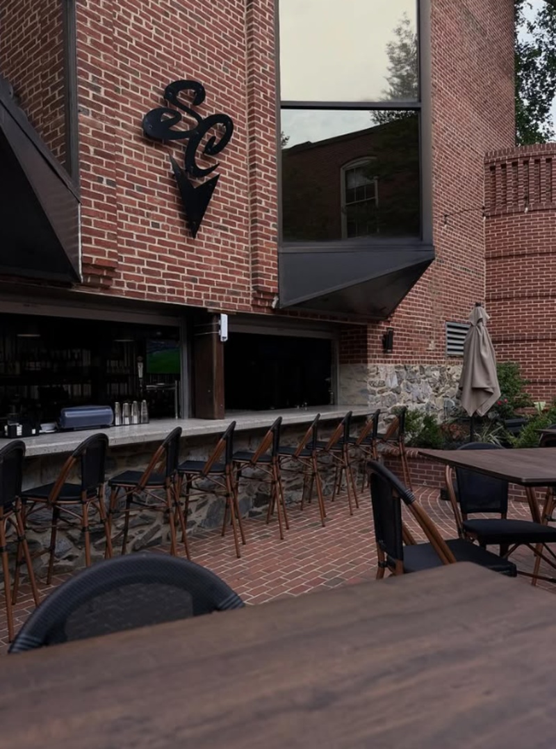 Outdoor patio at South County Brewing Co. in Lancaster, PA, with bar seating, high-top tables, brick walls, and open-air dining.