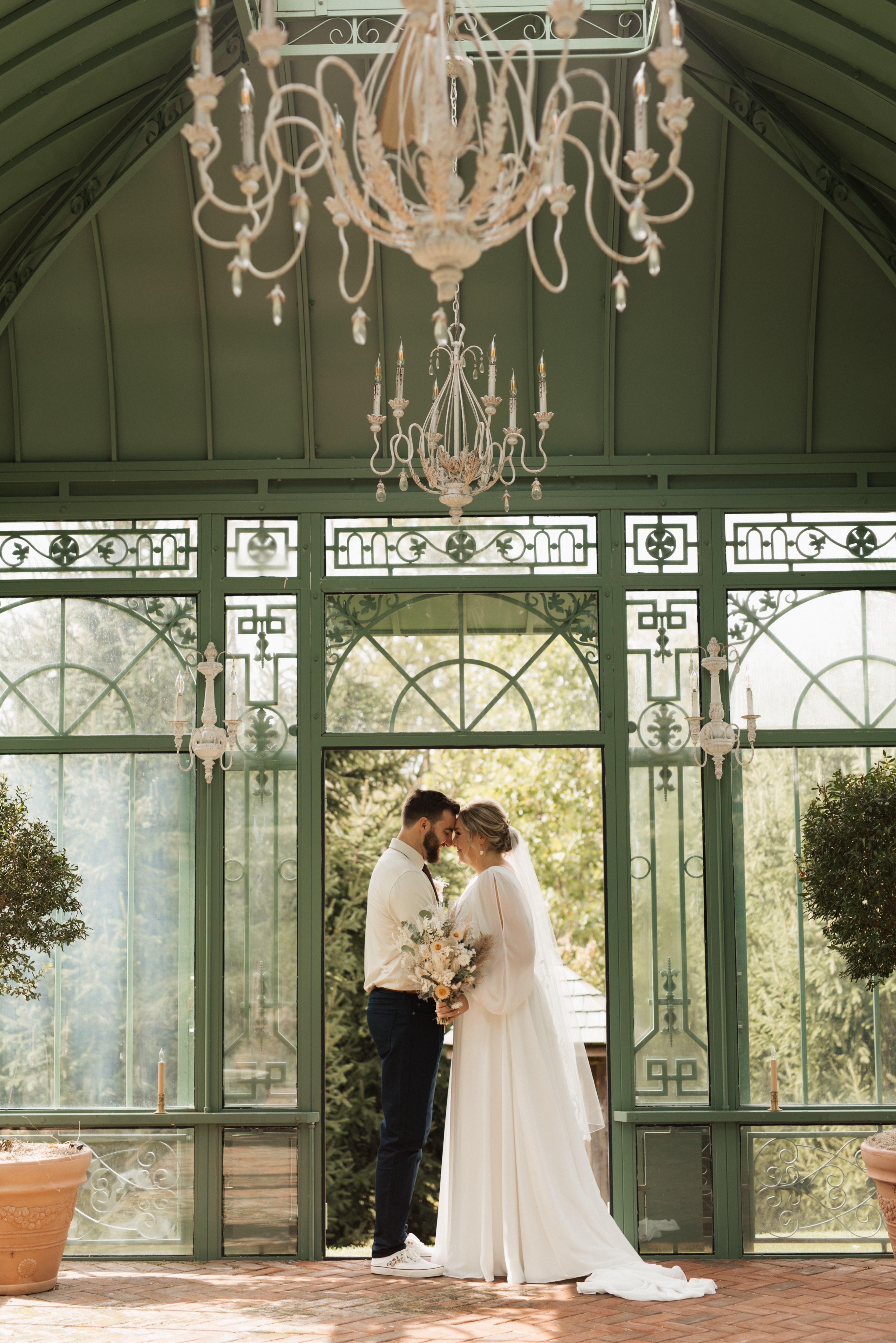 Romantic Greenhouse Wedding Portrait at St. Michael's Vineyard Bride and groom standing inside a greenhouse with chandeliers during a romantic garden wedding ceremony at St. Michael's Vineyard