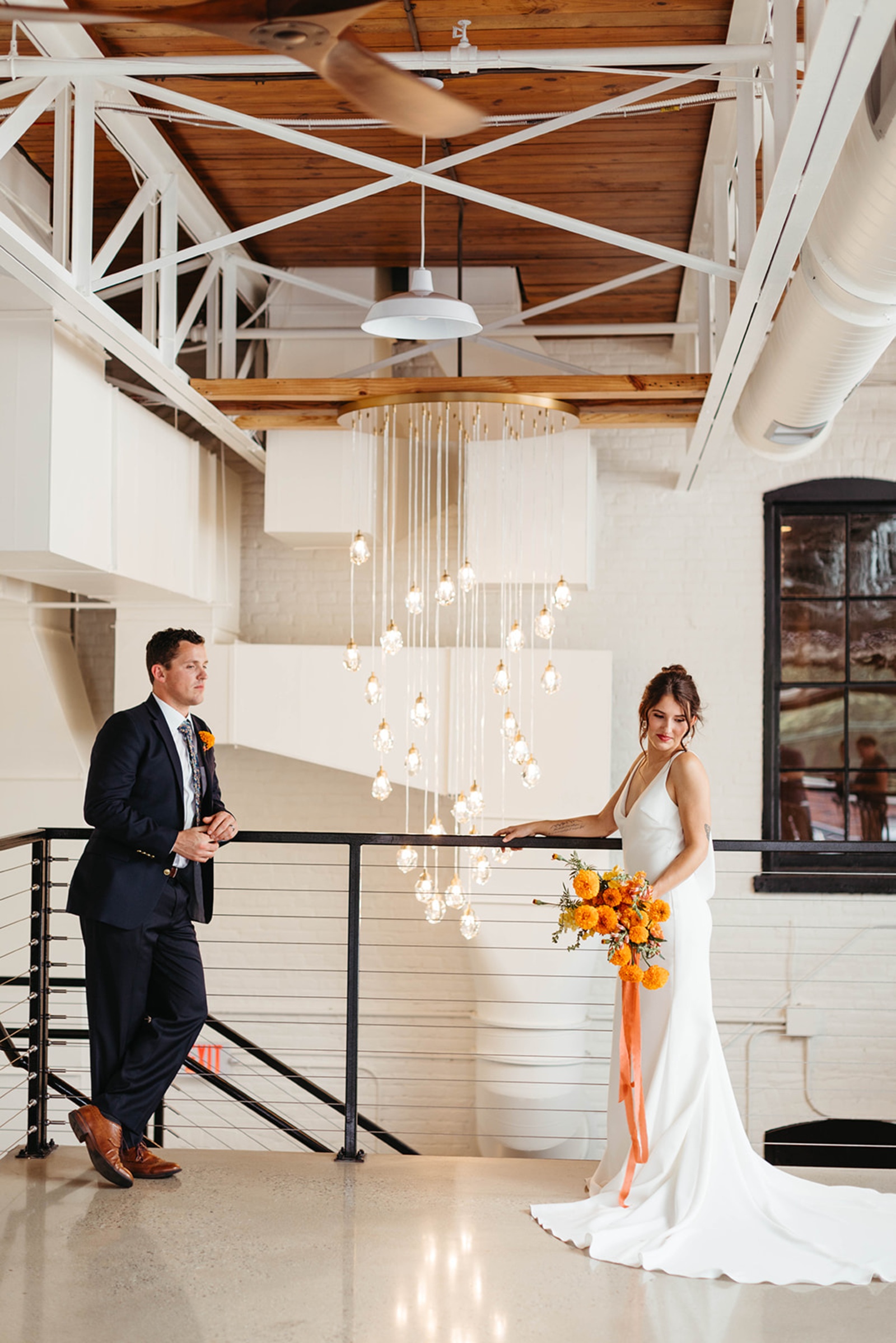 Bride and Groom at The Booking House Mezzanine Bride and groom posing on the mezzanine at The Booking House with industrial beams and hanging lights.
