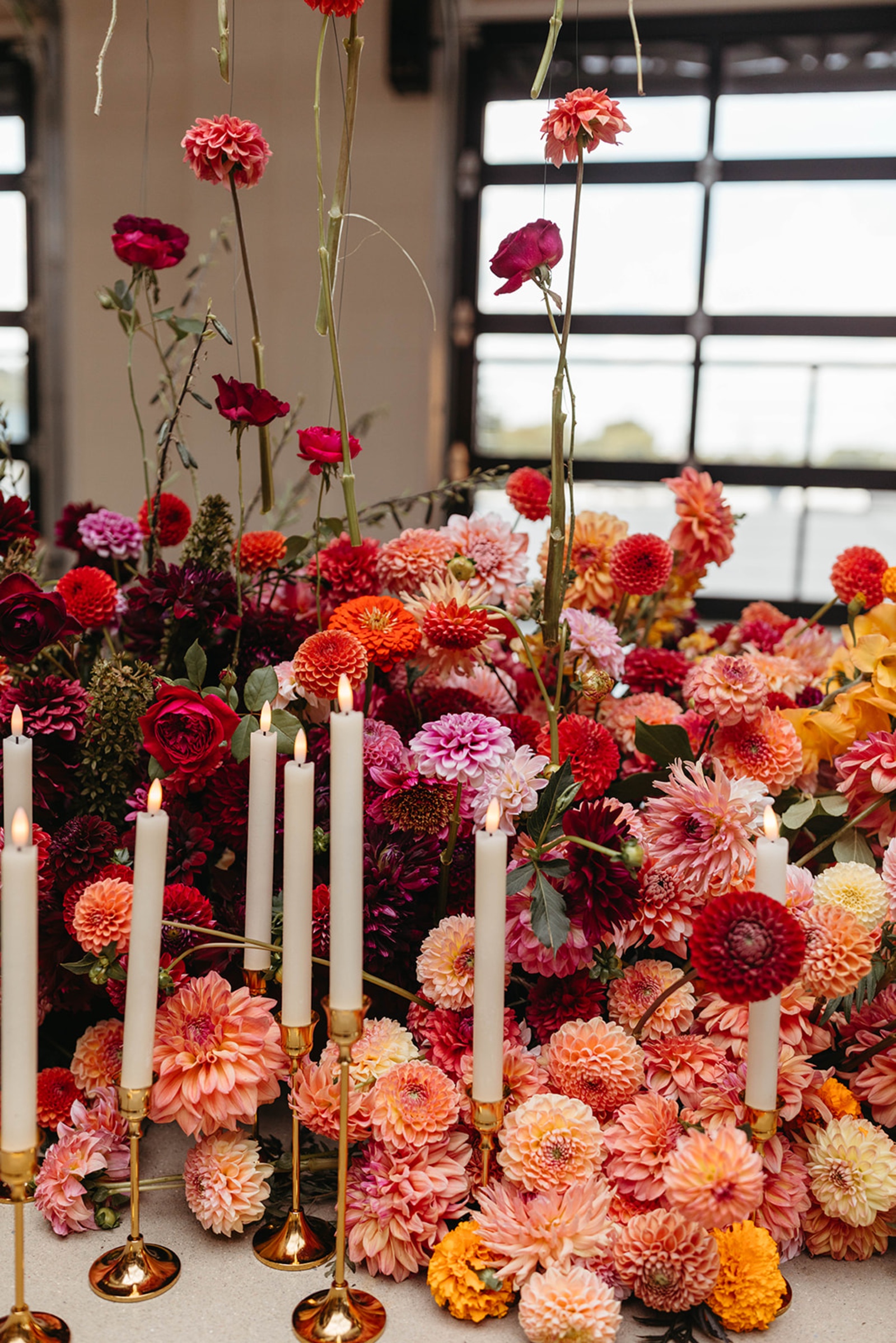 Colorful Wedding Florals and Candles Colorful wedding flowers in pink, orange, coral and burgundy paired with white taper candles.