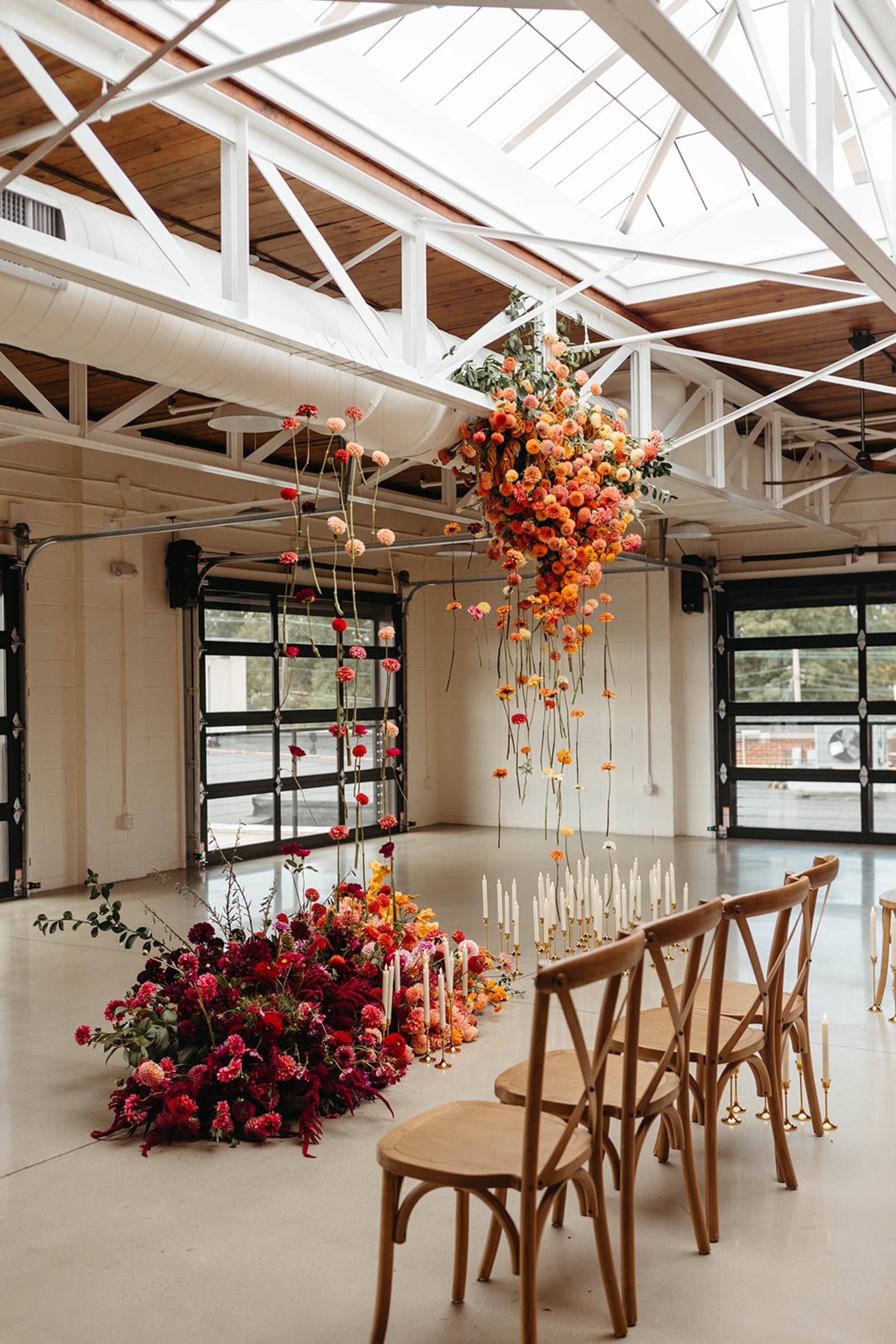 Colorful Ceremony at The Booking House Colorful ceremony setup at The Booking House with suspended florals, floor arrangements and wooden chairs.