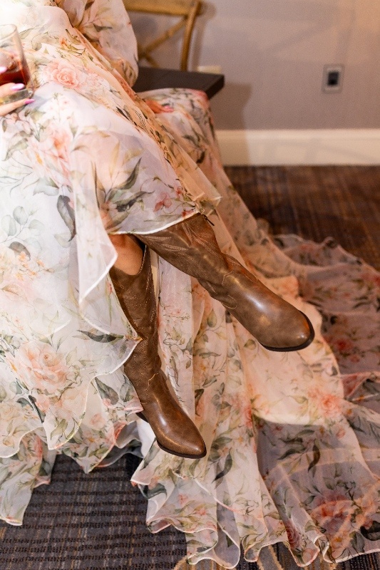 Bridal Boots and Florals: Western Wedding Style Close-up of a bride wearing brown cowboy boots under a flowing floral wedding gown, blending rustic country style with romantic Oklahoma!-inspired elegance.