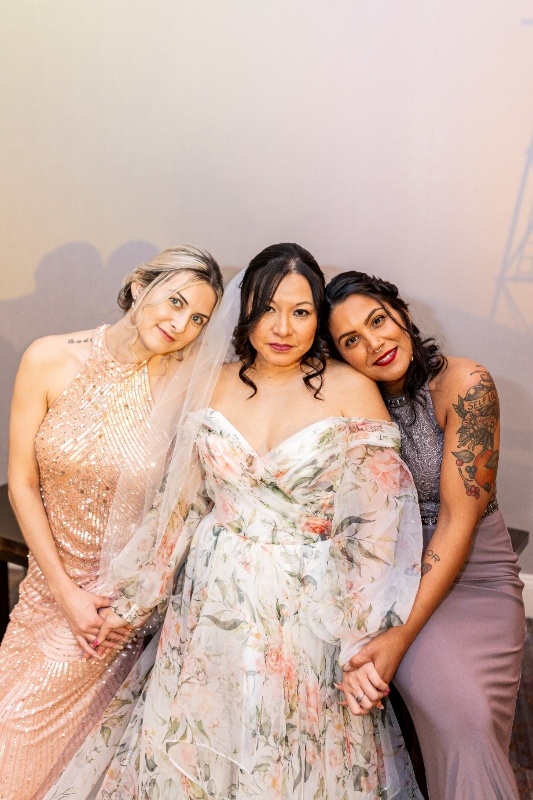 Bride and Bridesmaids in Coordinated Western-Inspired Gowns The bride in a floral gown poses with two bridesmaids dressed in blush and lavender tones, reflecting the soft, feminine palette of this Oklahoma!-inspired styled shoot.