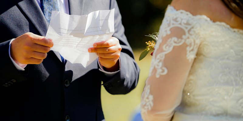 Couple exchanging rings during an intimate self-uniting wedding ceremony surrounded by close family and friends in a warm, emotional setting.